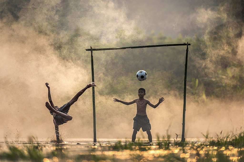 Asian children playing football in countryside