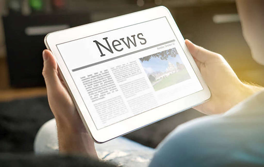 hands holding tablet with news page